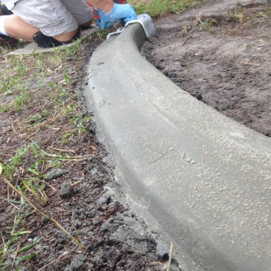 A person molding concrete to create a garden border