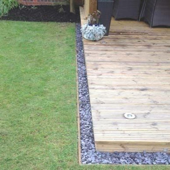 Garden stones separating a lawn and wooden deck.